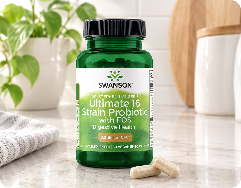 Bottle of Swanson Dr. Stephen Langer's Ultimate 16 Strain Probiotic with FOS beside two capsules on a marble kitchen counter